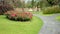Green lawns and artificial wood pathways in garden have flowers and trees growing