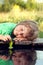 Green leaf-ship in children hand in water, boy in park play with