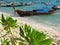 Green leaves and longtail boats on the tropical white sand beach - Thailand