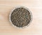 Green lentils in a small bowl on a wood table