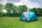 Green light dome tent without rain fly setup on campsite.