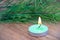 Green lighted candle against the background of fir branches.