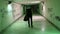 Green lighted tunnel with lettering on the walls. underpass