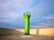 Green lighthouse surrounded by a concrete wall at sunset