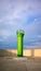Green lighthouse surrounded by a concrete wall at sunset
