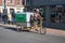 Green Link Couriers cyclist on tricycle riding on street to make deliveries