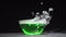 Green liquid boils giving off smoke in a glass bowl on a black background