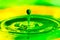 Green liquid paint drop splashing in yellow color