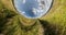 Green little planet revolves among clear blue sky and white clouds. Little planet transformation with curvature of space. loop rot