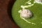 Green mashed soup with meatball in a rustic clay plate.