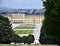 Green meadow slope, two rows of trees, beautiful flowerbeds, Schonbrunn Palace and a part of Vienna in the background.