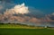 Green meadows landscape in countryside hills on impressive huge clouds in sky, beauty in nature