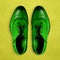 Green men`s shoes made of genuine leather on a yellow background. Minimal creative style