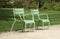 Green metal chairs in a relaxation area in a landscaped park