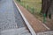 Green metal railing on the edge of the park by the road made of cobblestones. A metal ornate historic low fence symbolically separ