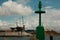 Green Metallic Lighthouse, Blue Sky with Clouds and Shipyard in