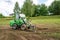 A green mini skid steer loader clear the construction site. Land work by the territory improvement. Small tractor with a ground