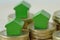 Green miniature houses on coin stacks - Concept of real estate investment, mortgage, home insurance and loan, eco-friendly house