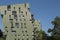 A green modern residential apartments building next to the Wiener Gasometer on a blue sky