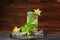 A green mojito with lime. A mojito cocktail on a wooden background. An alcohol mojito with mint, carambola and ice. Copy space.