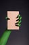 Green monster hand with black nails holding blank piece of cardboard