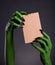 Green monster hands holding empty piece of cardboard