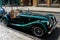 Green Morgan vintage cabriolet parked on a brick road on a sunny day