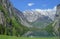 Green mountain lake Mittersee. Mirroring the Alpine snow-capped peaks.