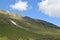 Green mountain side view with snow remains