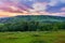 Green mountain slope with houses on it against the background of a dawn or sunset sky. place for rest and travel