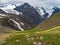 Green mountain slope, a view of a deep mountain valley with stunning snow peaks in the background