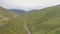 Green mountains path aerial. Narrow way from hill to cloudy peak. Cinematic nobody nature landscape