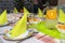 Green napkins arranged on plates in the shape of a triangle, lemonade made of water and orange slices in a large jug, salads visib