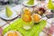 Green napkins arranged on plates in the shape of a triangle, lemonade made of water and orange slices in a large jug, salads visib