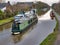 A green narrowboat Gregory`s Girl passes along the Lancaster Canal near the Moss Lane Bridge at Garstang, Lancashire, England