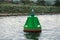 Green navigation buoy floating on sea water