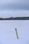 Green navigational spar buoy on a frozen lake