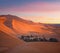 Green oasis with palm trees over sand dunes in Erg Chebbi of Sahara desert on sunset time in Morocco, North Africa