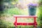 Green old bucket with garden campanula flowers on red little stool over summer nature background