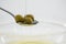 Green olive oil being poured in spoon