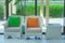 Green and orange pillows on white weave chair setting on concrete floor in the lobby of hotel.