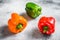 Green, orange and red bell peppers. Gray background. Top view. Space for text