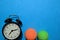 Green and orange tennis ball, and alarm clock indicating workout plan on blue background.