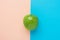 Green organic apple on duotone peachy pink mint blue background. Vitamins healthy diet summer detox vegan superfoods