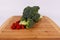 Green organic broccoli crown and florets sweet cherry tomatoes on a light wood cuttingboard