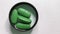 Green oval pills in the lid on a white background