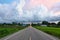 Green paddy field along the highway road under the evening sky in a rainy day.