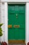 Green painted front door with white frame and brass furniture