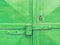 Green painted obsolete metal garage gate with armored lock housing