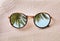 Green palm leaves reflecting in sunglasses on sandy beach, top view